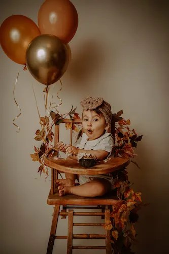 Bébé assis dans une chaise haute, décor d’anniversaire simple et naturel.